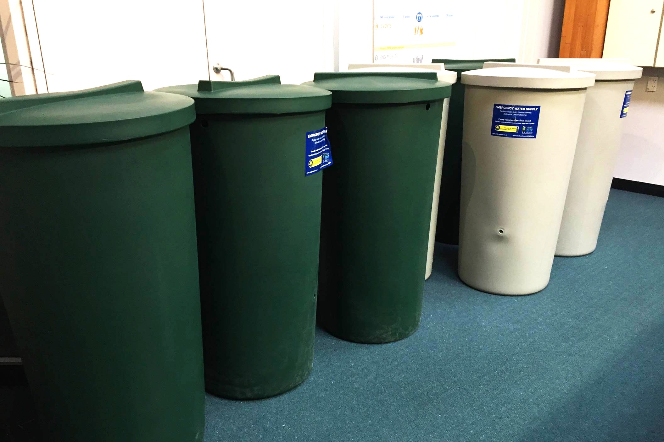 A collection of green and white emergency rainwater collection tanks.